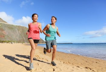 Runners running on beach. Jogging couple training on beach in fu